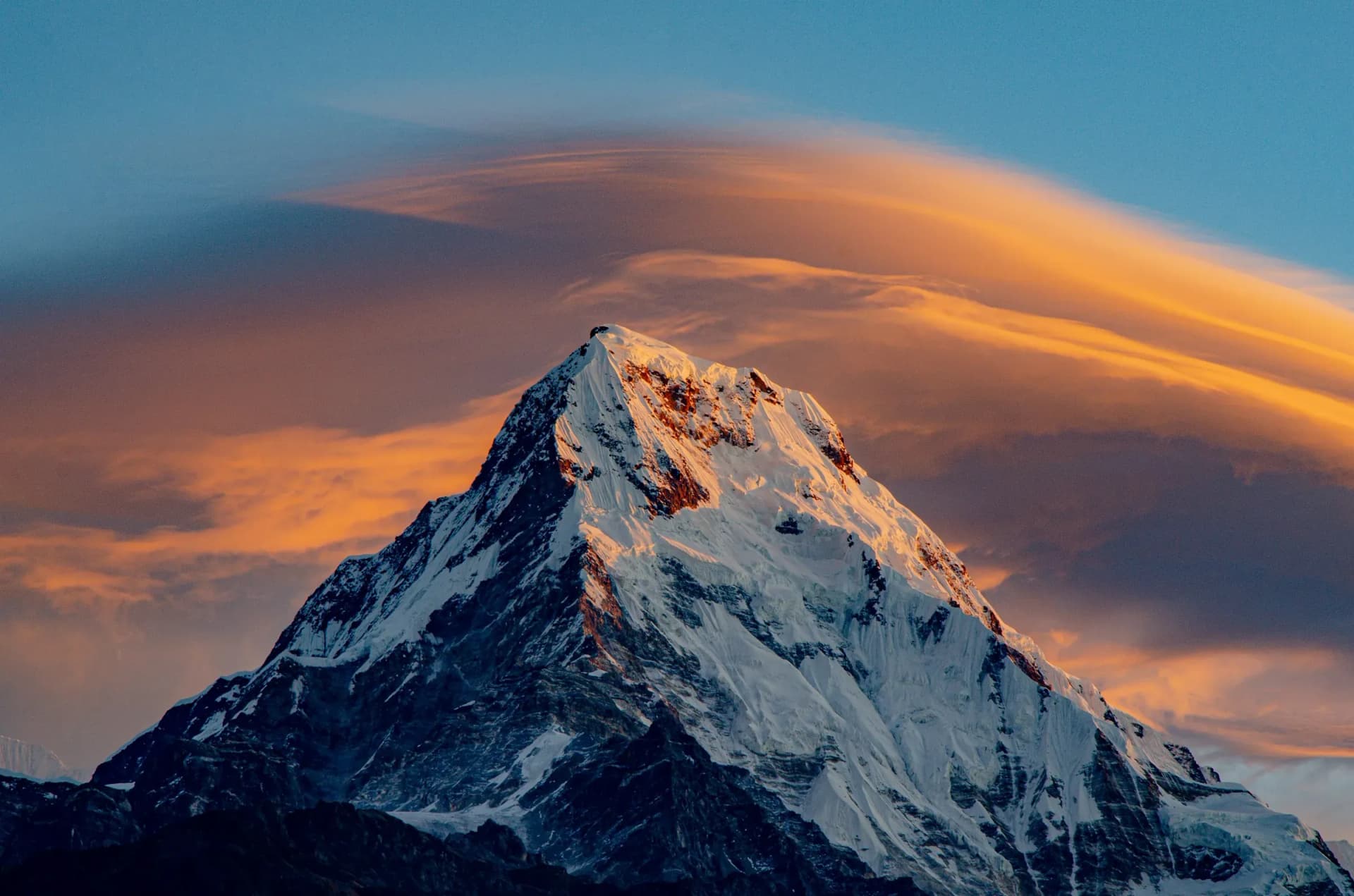 Snow peak of the Annapurna range under a golden lenticular cloud