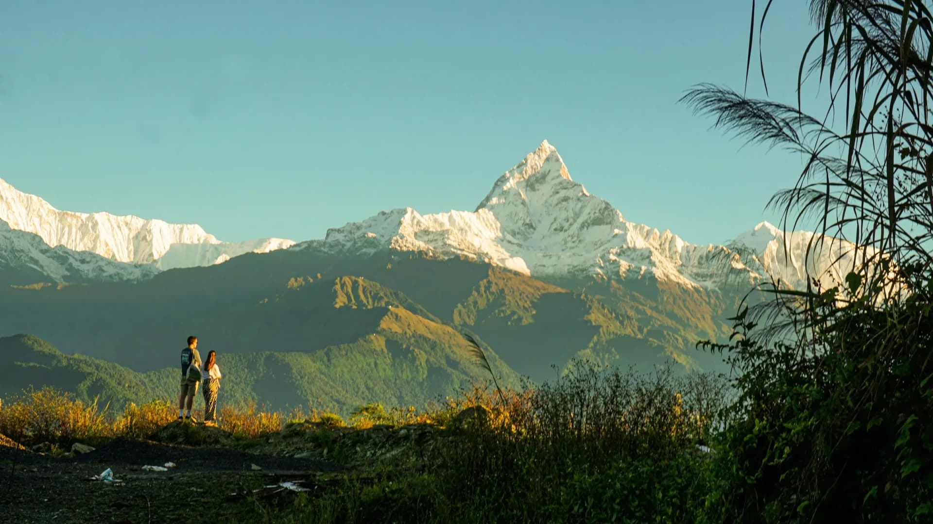 A couple watching sunrise over Machapuchare and the Annapurna range