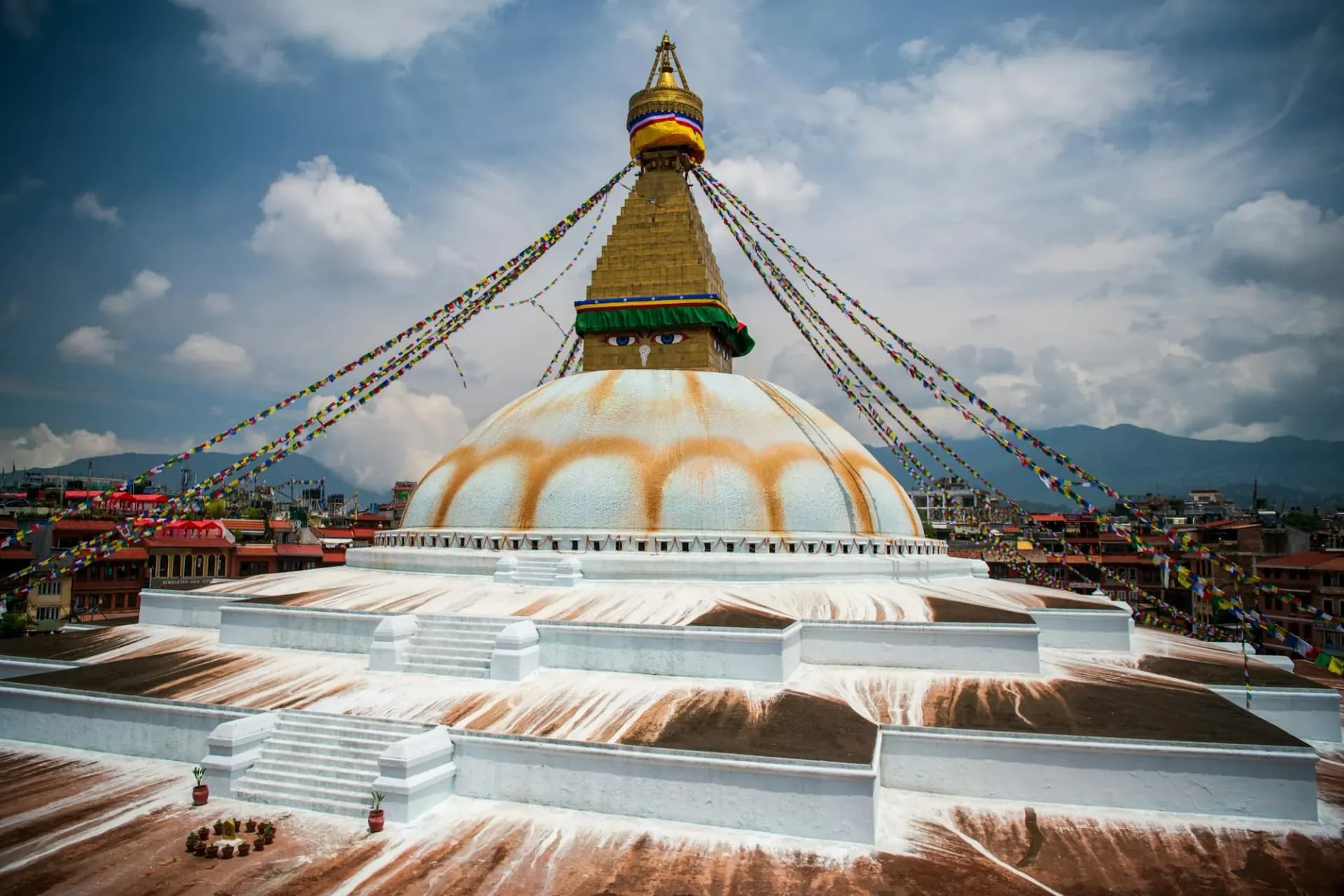 The white dome and gilded tower of Boudhanath Stupa under summer clouds