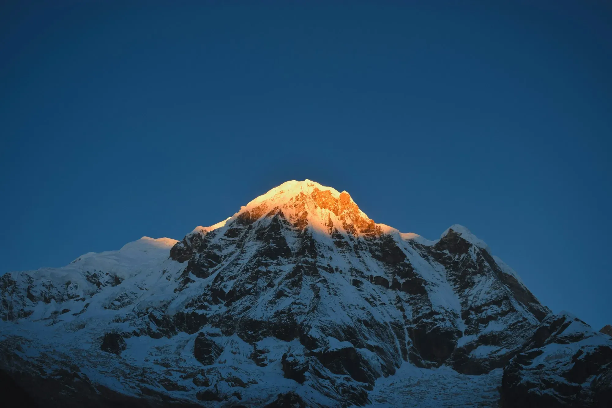First light on a snow-covered Himalayan summit above a glacier