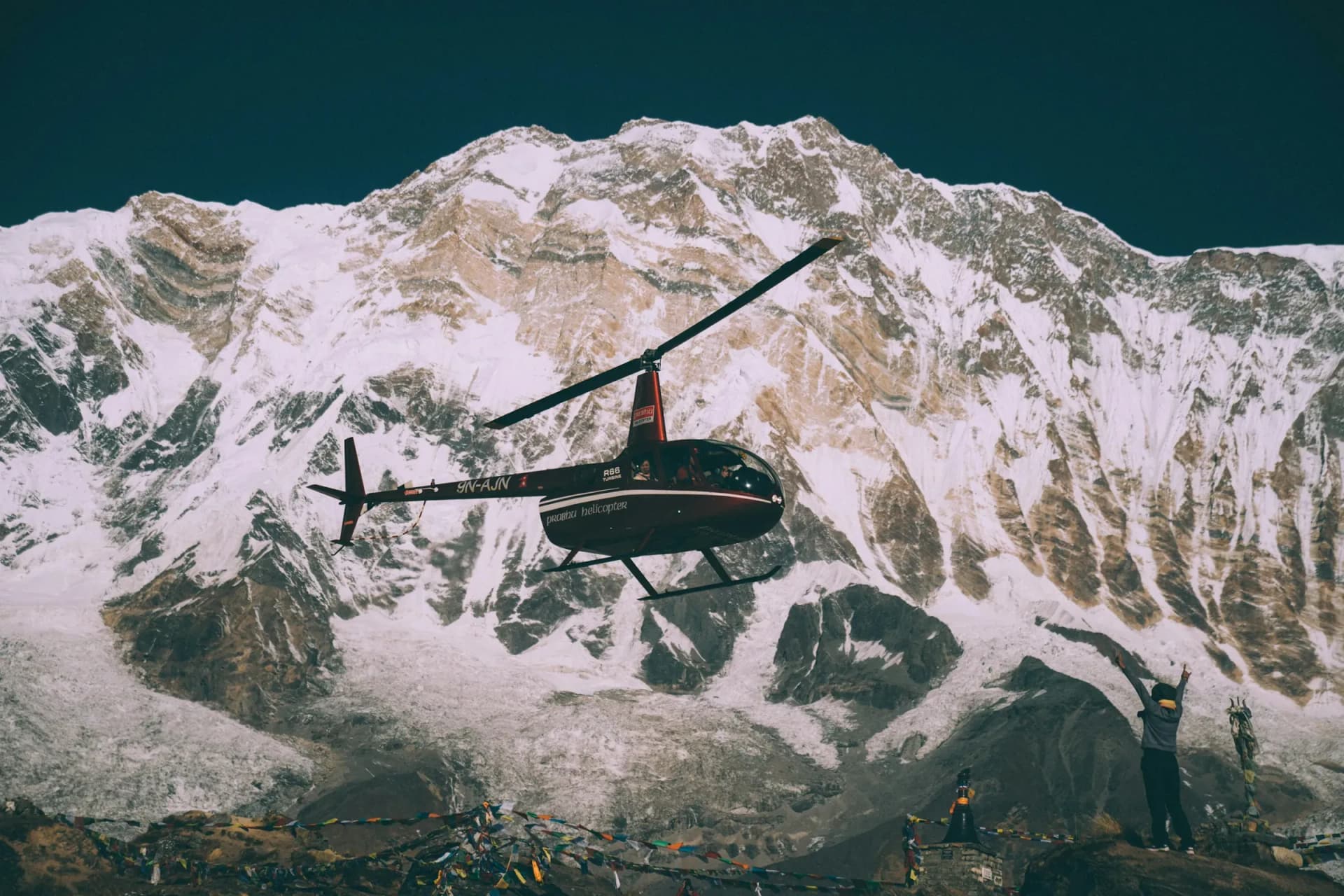 Helicopter flying in front of a Himalayan ice face