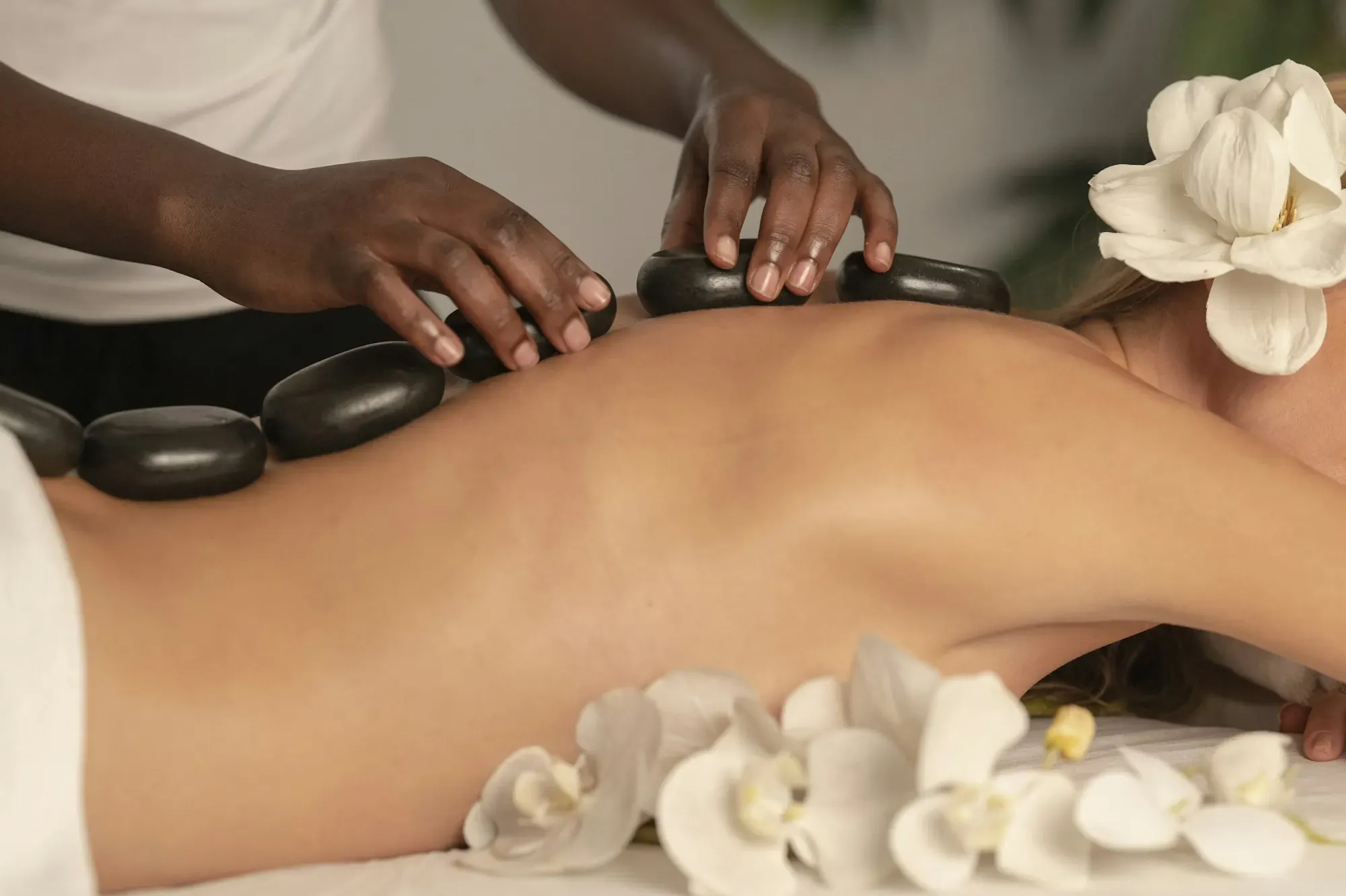 Hot stone massage with white orchids in a calm spa room