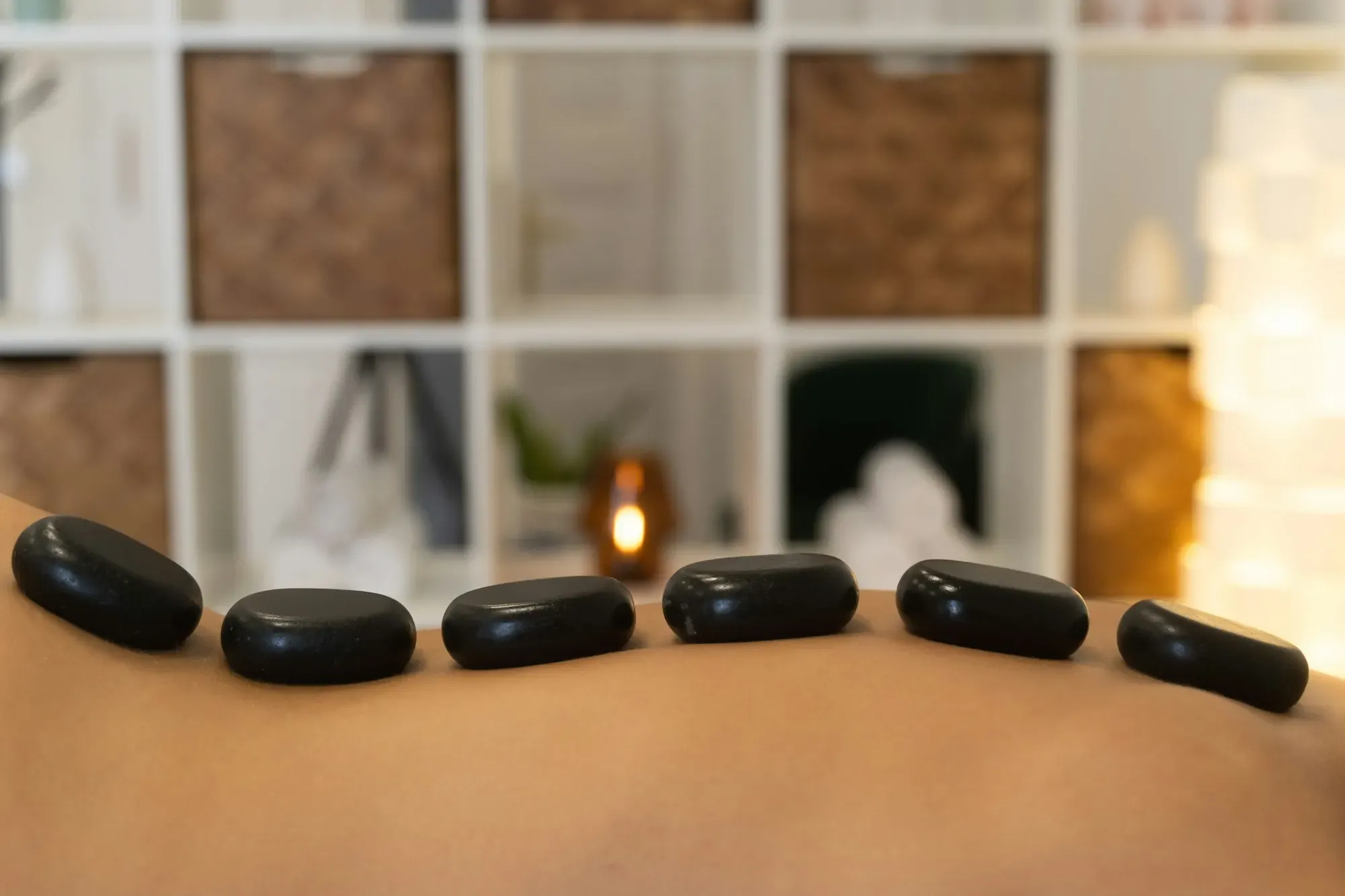 Warm basalt stones laid along the back in a candle-lit spa room