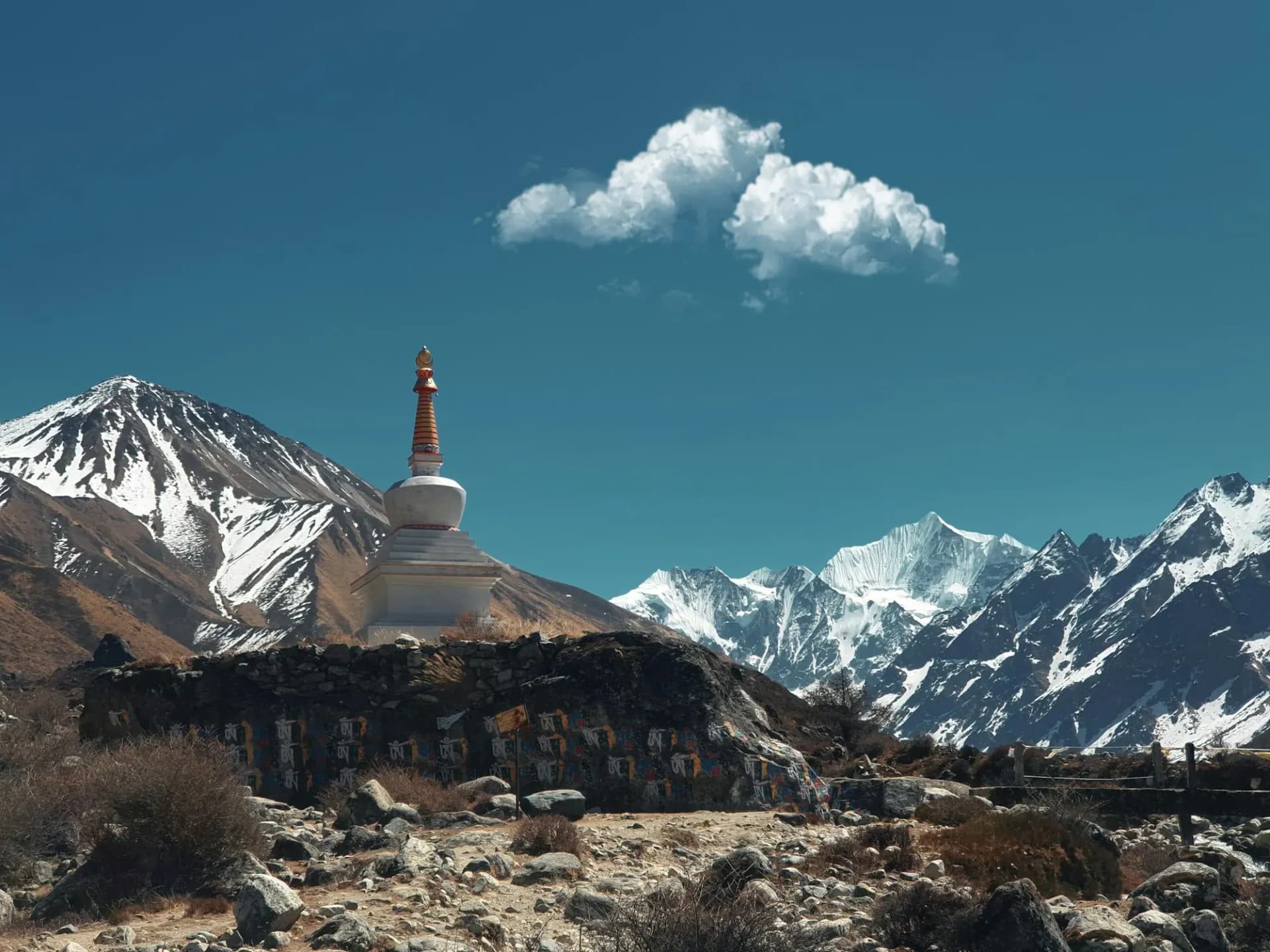 White chorten and mani wall below snow peaks in the Langtang valley